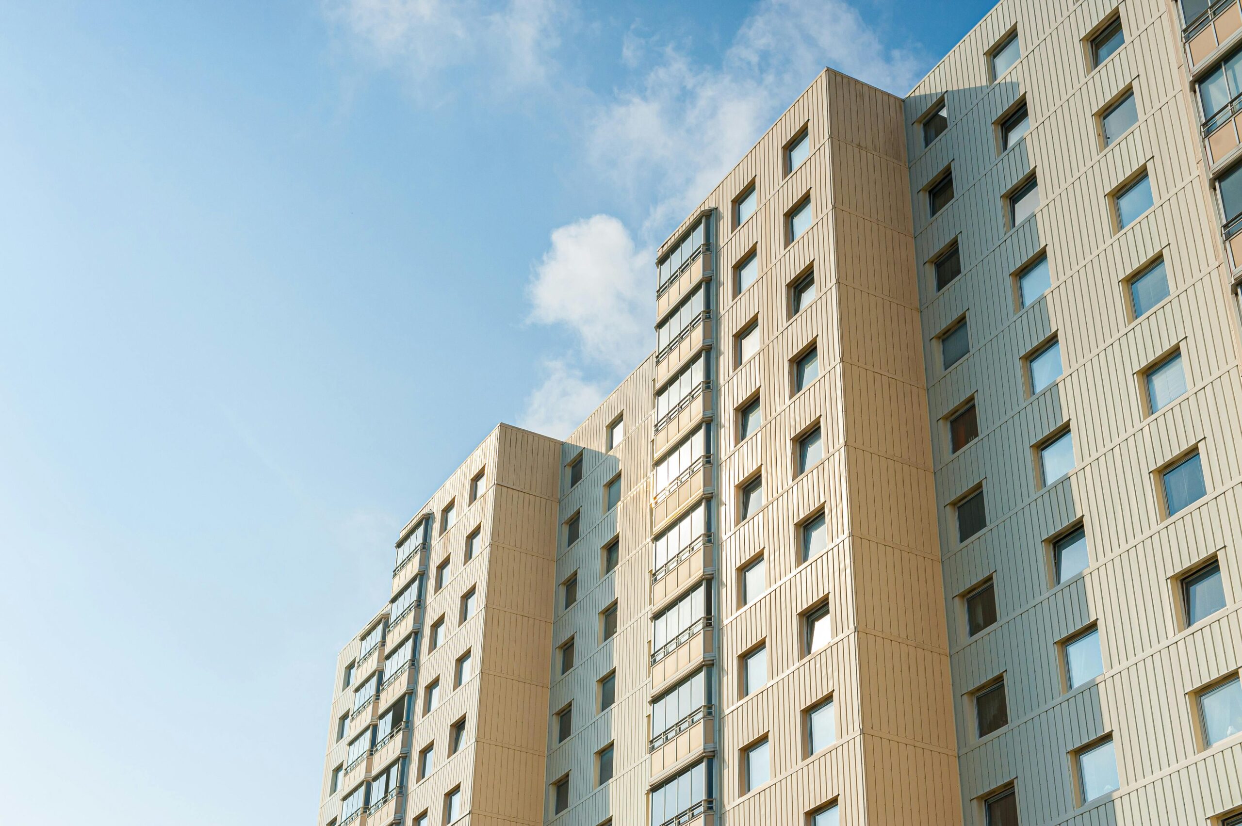 Exterior view of a modern high-rise building with multiple windows against a clear blue sky.